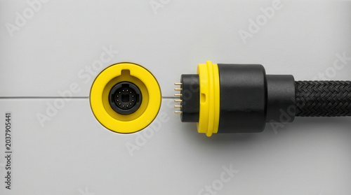 Yellow connection port and cable with multiple pins visible, showcasing a close-up view of the electrical interface on a gray surface