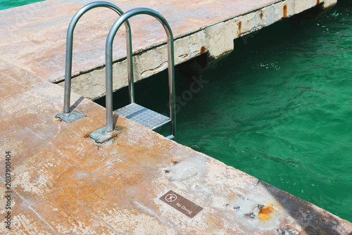 Dilapidated dock with ladder and water.