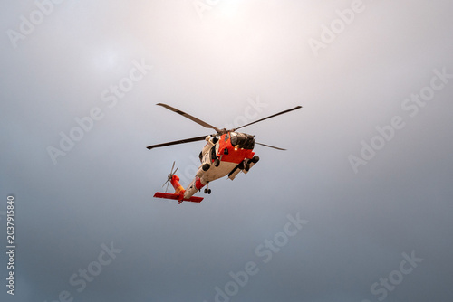 Search and rescue helicopter flying overhead against cloudy sky