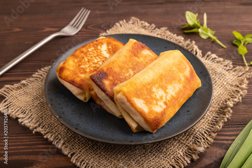Fried crispy pancakes with meat and cheese on brown wooden and linen textile. side view, close up