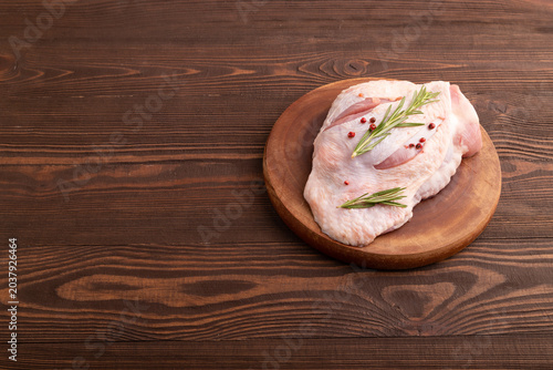 Raw Turkey Thigh with spices on cutting board on brown wooden. side view, copy space