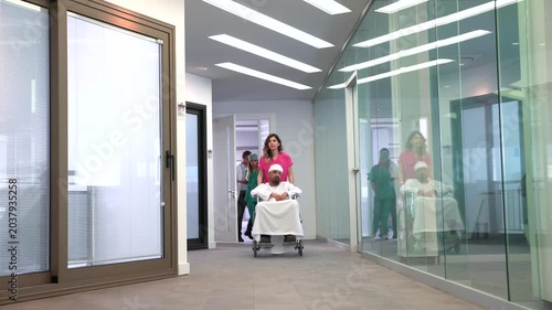 Nurse pushing patient on gurney down hospital corridor with medical staff