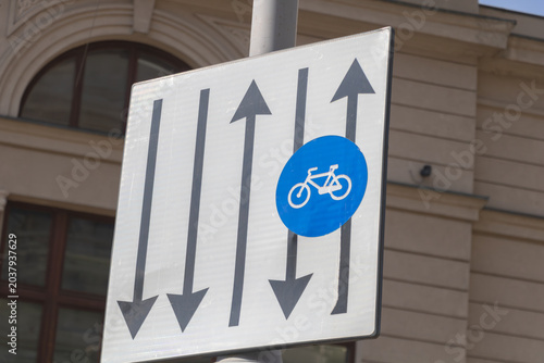 Close-up view of a bicycle lane traffic sign with directional arrows mounted on a city street in Bucharest,