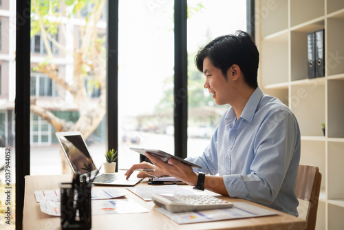 The businessman is reviewing work on a tablet at his desk.