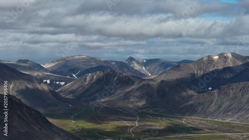 Top View over vast mountains and valley routes in Provideniya, Chukotka, Russia. Drone tracks along ridges above tundra lowlands in daylight, highlighting rugged wilderness. UAV aerial footage