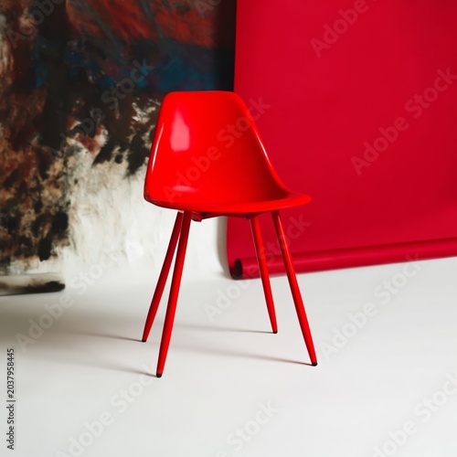 Bright Red Chair Stands Alone on White Surface Against Gray Background in Ind...
