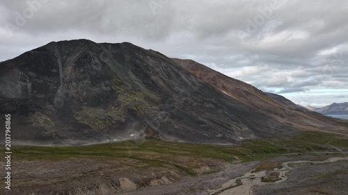 Dramatic ridge and braided river leading toward the sea in Russia, Chukotka, Provideniya. Drone establishing shot pans right, opening a remote Arctic coastline and horizon line far offshore.