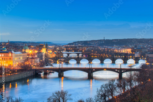 Фотография prague bridges over vltava river at blue hour with city lights and charles bridg