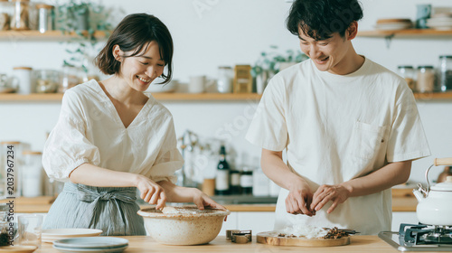 カップルが笑顔で料理する明るいキッチン