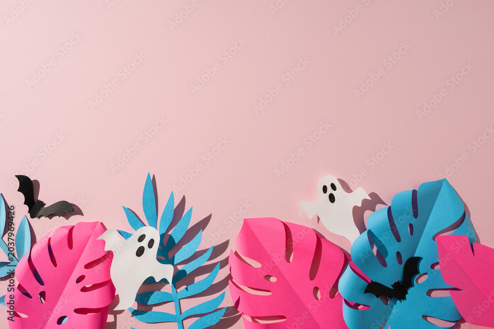 Obraz premium Tropical Halloween paper craft with pastel monstera leaf, ghost cutouts and bats on pink background