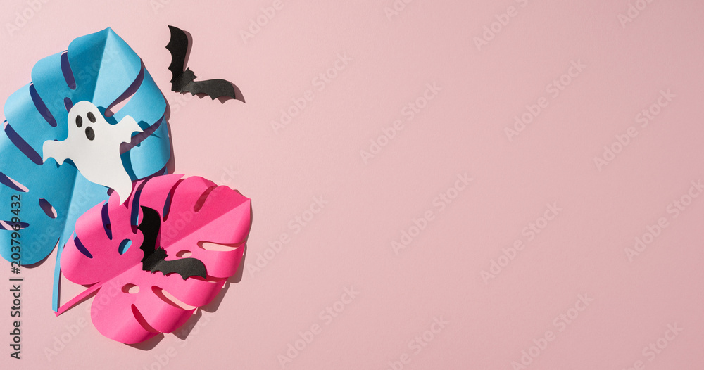 Obraz premium Tropical Halloween paper leaf with ghost and bat decorations on banner pink background