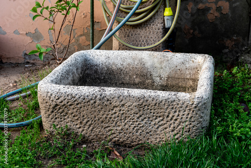 rustic garden stone container near garden tap in garden