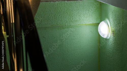 Foto Round light illuminating a textured green wall in a building corridor, casting s