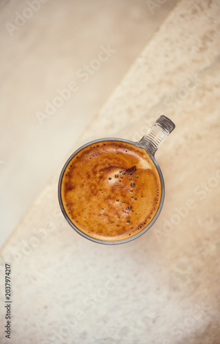 Coffee cup from above, Espresso foam texture, creamy coffee, rich, freshly brewed cup of hot latte. Top view of cappuccino milk foam closeup. Creamy coffee macro shot, on a marble table, top view