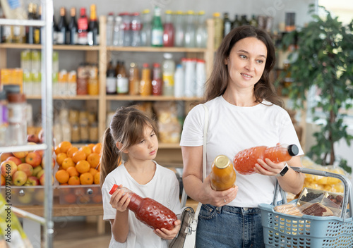 Foto Mother and daughter choose tasty juice together in grocery section of a supermar