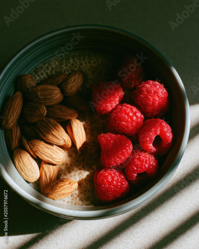 Almond raspberry seed pudding bowl with sunlit shadow on dark surface