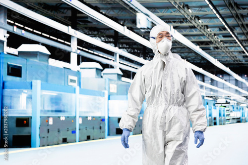 Bild auf Leinwand Engineer man walking in microchip manufacturing plant laboratory, wearing protective gear, Integrated circuits industrial factory professional in cleanroom checking automated machinery yield output