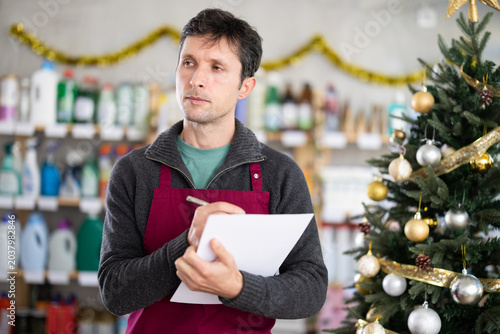 Slika na platnu Male salesman makes notes on paper - keeps track of the receipt and expenditure
