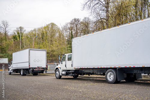 Foto Day cab middle duty white semi trucks with roomy bo trailer standing on the stre