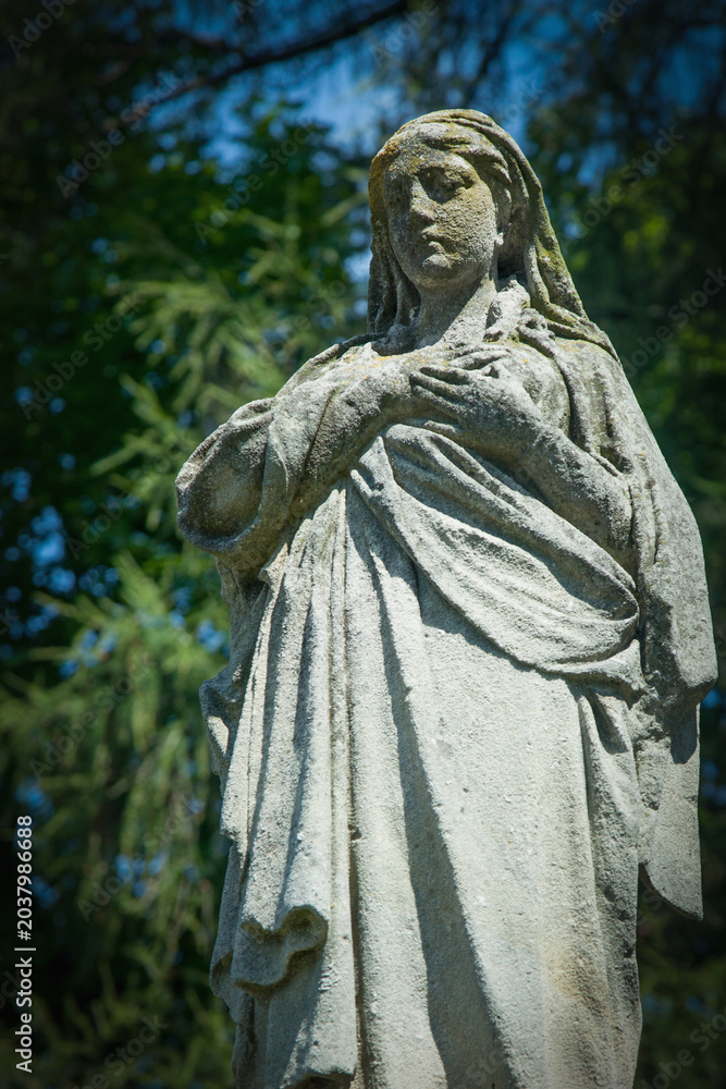 Obraz premium Stone angel statue standing peacefully in cemetery garden.