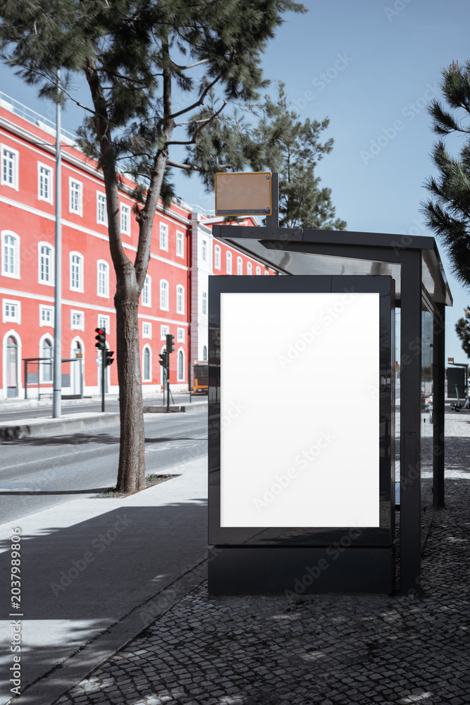 Φωτογραφία Empty backlit poster panel on black bus stop shelter beside red historic buildin