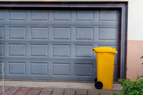 yellow and black recycling bins in front of garage door