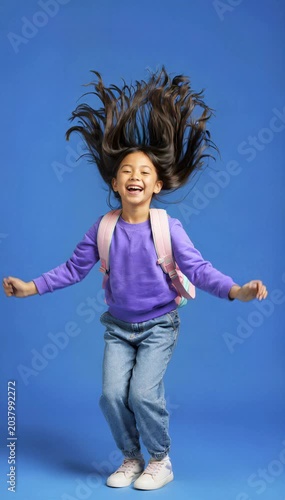 Joyful Young Girl Jumping with Backpack on Blue Background, Expressing Excitement and Back to School Success