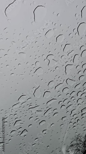 Raindrops on car window under cloudy sky