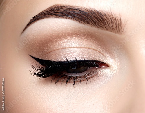Close-up of a perfectly made-up eye, showing a sharp eyeliner wing, full lashes, and a flawlessly shaped eyebrow