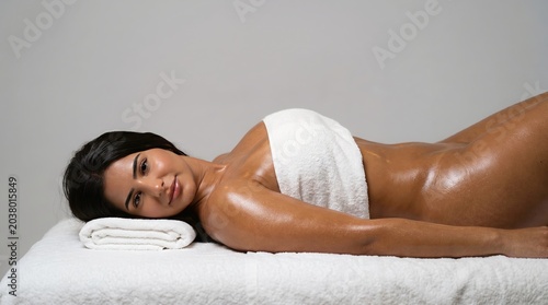 Beautiful woman with radiant, glowing skin enjoying a relaxing spa body treatment on a comfortable massage table, embodying self-care and serene well-being in a tranquil setting