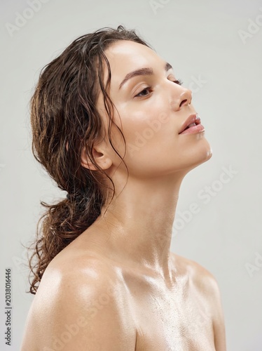 Captivating close-up of a radiant young woman, her skin dewy and hair damp, embodying natural beauty and a sense of wellness, with a peaceful and fresh expression