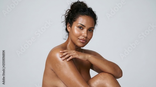 Captivating portrait of a beautiful woman showcasing glowing, healthy skin and natural beauty, exuding confidence and a peaceful demeanor against a minimalist backdrop