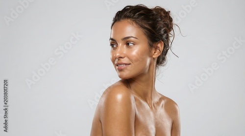 Smiling woman with fresh skin and wet hair looking relaxed against neutral background for beauty and wellness branding