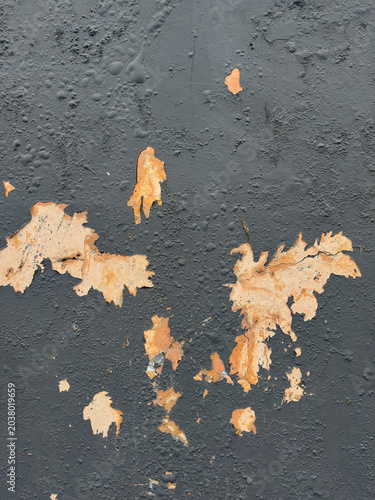 Time-worn dark surface with paint delamination revealing contrasting rustic underlayer beneath