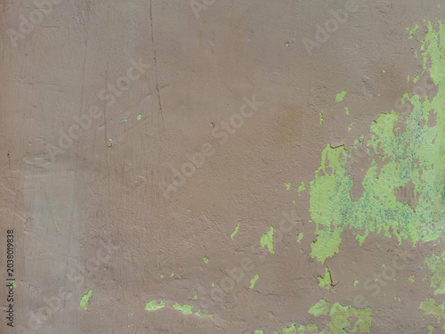 Worn plaster facade showing earthy brown base contrasting with vibrant green organic patterns