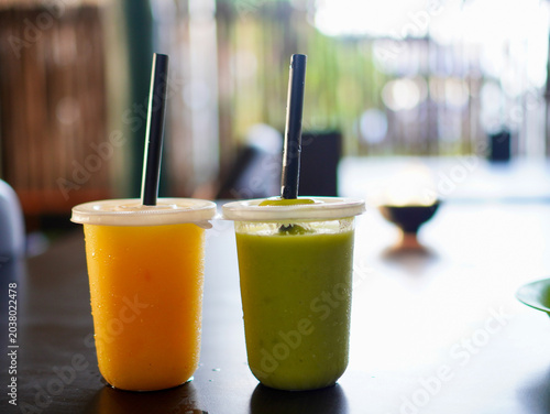Принти на полотні Refreshing mango and avocado juices served in takeaway cups on a table, offering