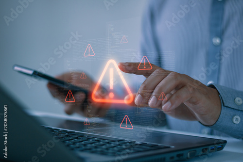 Obraz na płótnie Businessman respond to digital security alert on laptop and smartphone, cybersecurity warning, cyber threat detection, risk management, data breach prevention concept