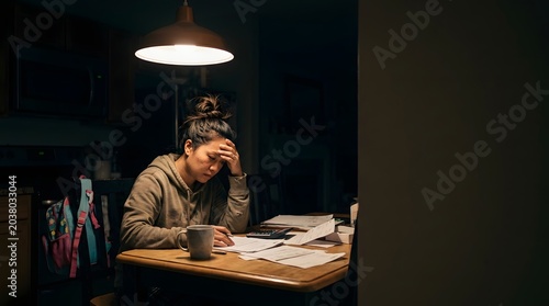 Stressed woman working late at night dealing with financial stress financial paperwork accounting