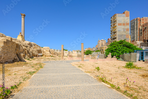 Fotografie The ancient Roman monolithic column rises above Egyptian sphinx figures and ruins at the archaeological site of Pompey's Pillar in Alexandria Egypt