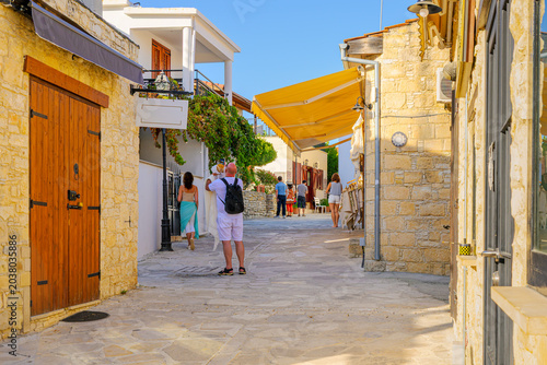 Tourists shop and sightsee on a picturesque alley in the historic medieval mountain town of Omodos, in the Troödos Mountains of the Limassol District on the Mediterranean island of Cyprus.