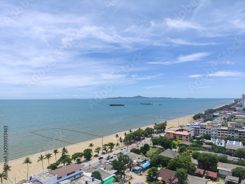 Vibrant coastal cityscape with sandy beach palm trees and distant ships under blue sky