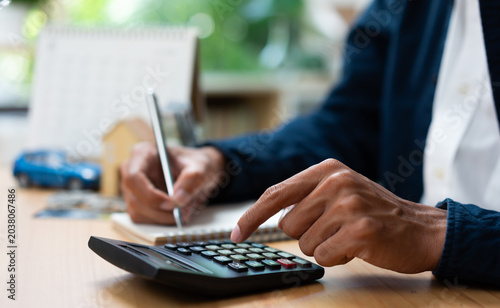 Businessman calculating car insurance and financial planning with calculator and documents at office desk.