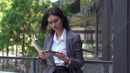 Smiling businesswoman using smartphone outdoors near office