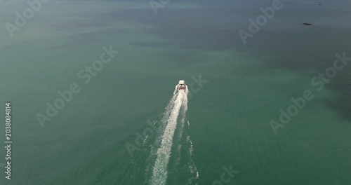 Aerial view of a tourist boat traveling toward Koh Rong Island, leaving a long, white wake trail across the vast, open sea.