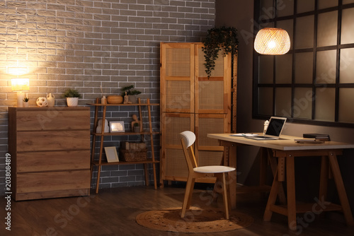 Obraz na plátně Interior of office with workplace, shelf unit and glowing lamps