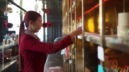 Female bartender arranging glasses on shelf before bar opening