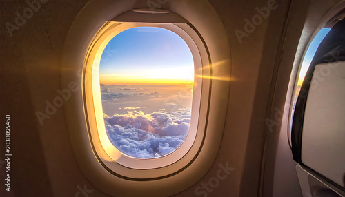 View from airplane window at sunset, clouds illuminated by golden light, travel and adventure concept