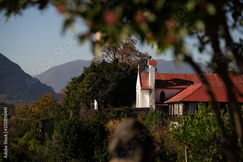 Принти на полотні Monasterio de techo rojo fotografiado en un paisaje otoñal.