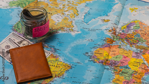 Plan travel by saving money in a jar on a map with cash wallet