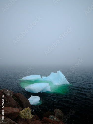 Beautiful iceberg floats in the fog and mist of Twillingate Harbor of Newfoundland-Labrador